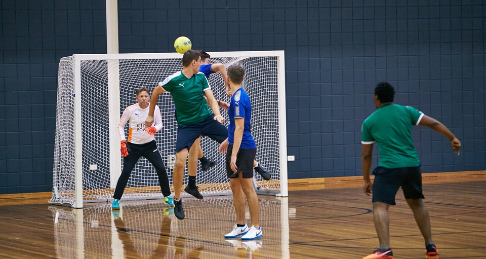 Two players contesting the ball near the goals in a men's futsal game