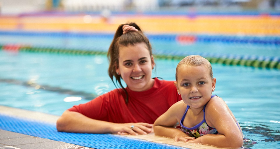 Swim instructor with student at the water's edge of the pool