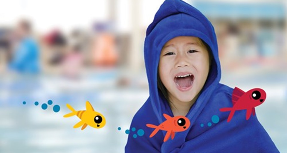 Happy young child poolside wearing a hooded towel