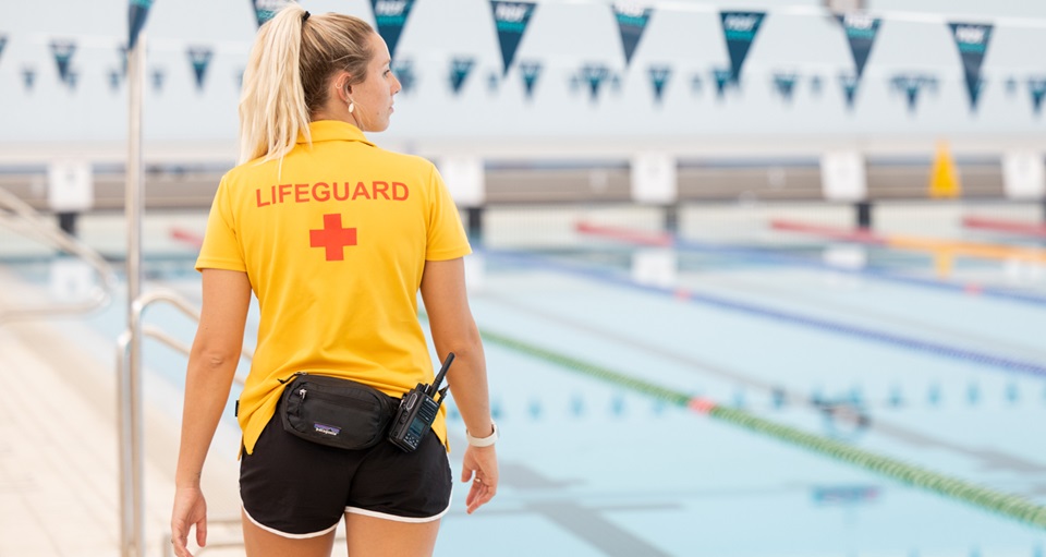Lifeguard patrolling from the side of a indoor 50m pool