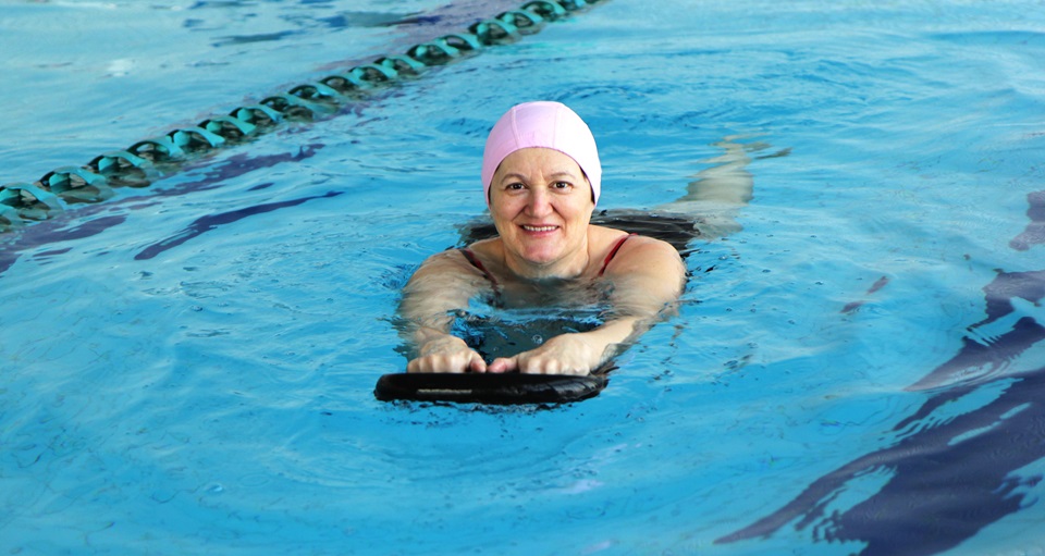 Happy woman lap swimming with a kickboard