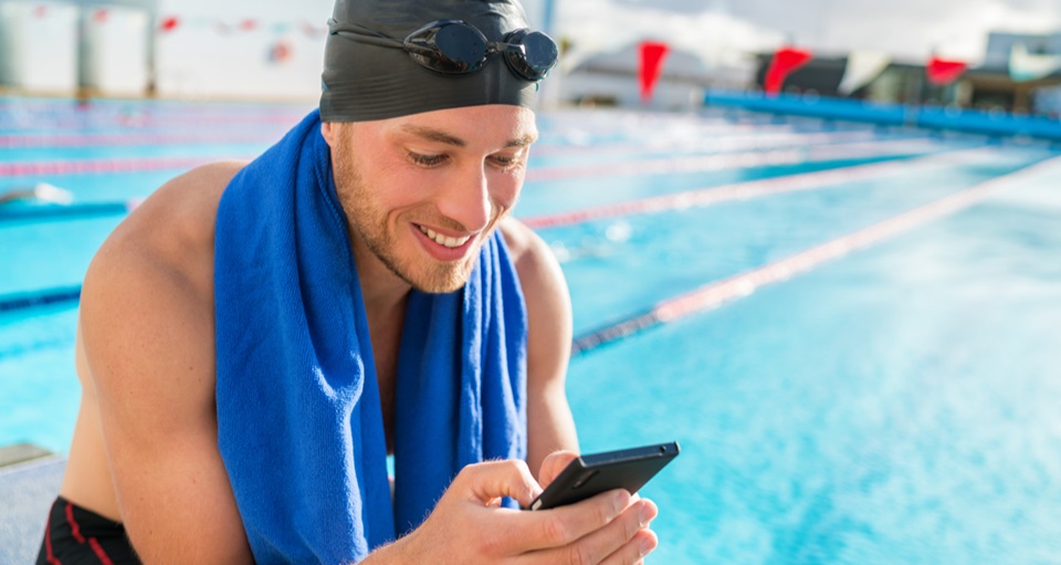 Lap swimmer sitting poolside viewing phone