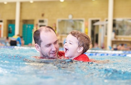 Swim Instructor teaching a happy toddler to swim