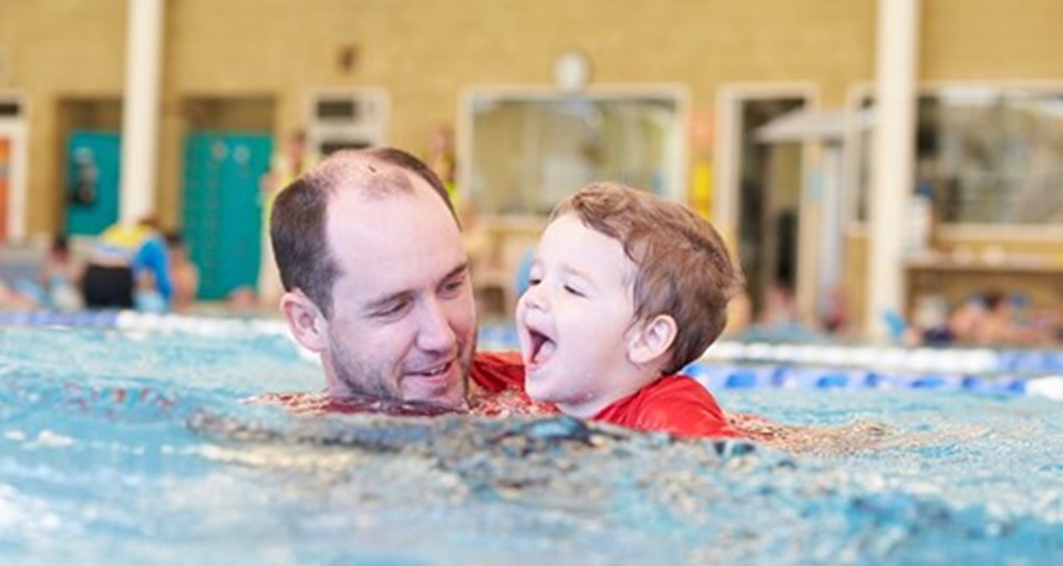 Swim Instructor teaching a happy toddler to swim